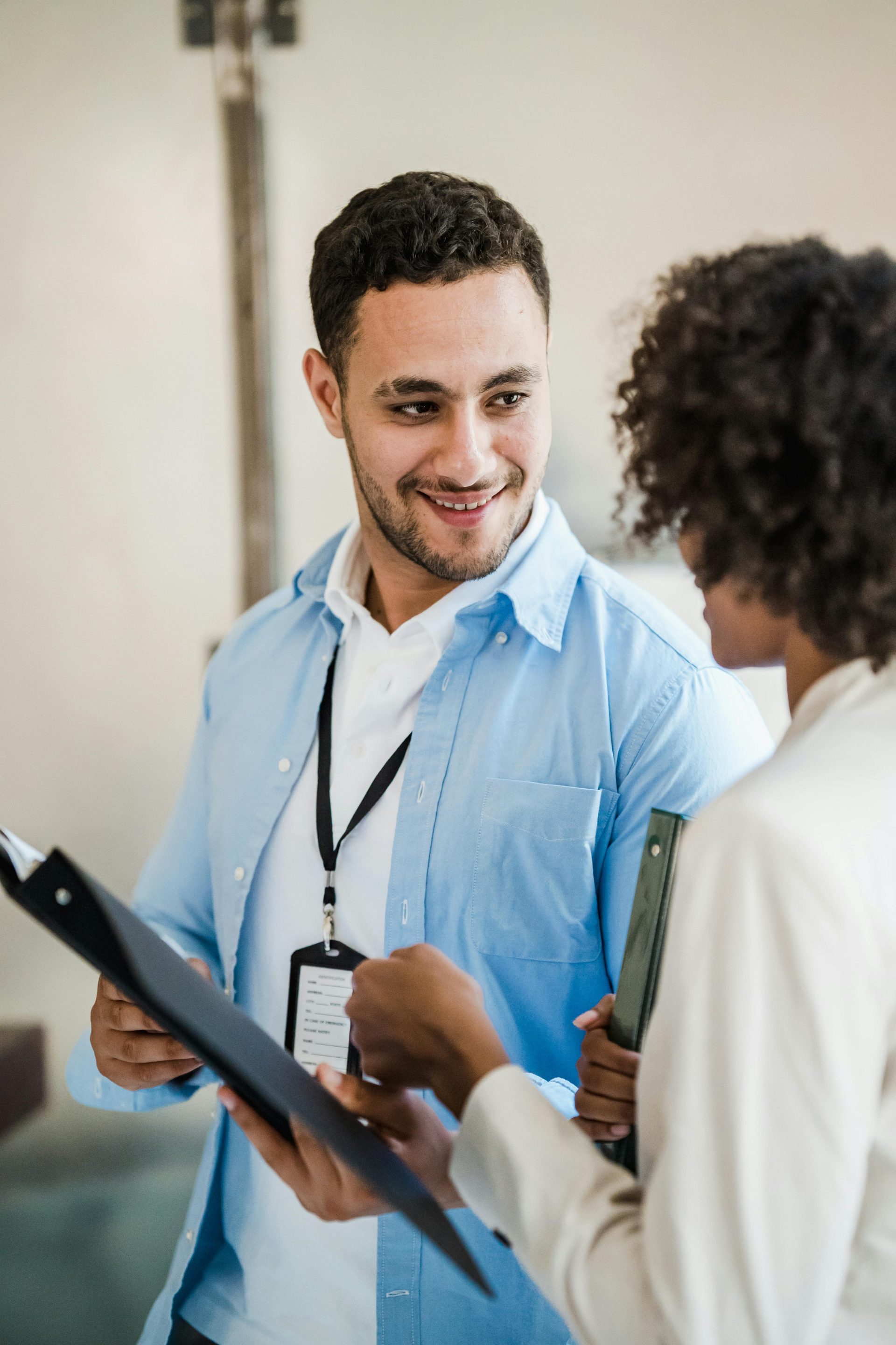 Two professionals engage in a conversation, reviewing documents in a modern office setting.